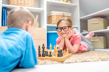 Adorable Little Girl Playing Chess With Her Brother In The Kids Room