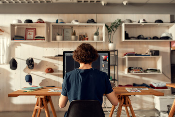 Poster - Excellence in graphic. Portrait of male worker sitting by desk, drawing sketches logo design using pc. Young man working at custom T-shirt, clothing printing company