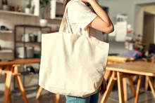 For Your Brand. Cropped Shot Of Female Worker Posing With Custom Shopper Bag In The Store. Young Woman Working At Custom T-shirt, Clothing Printing Company