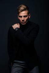 Canvas Print - Formally dressed man with sharp jawline in his 20's posing in a studio in front of a black background.