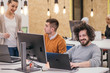 © qunica.com - Coworkers, employees working and discussing a project they are preparing while typing on a laptop and looking at pc, computer.