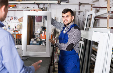 Wall Mural - Production worker in coverall demonstrating different PVC windows to customer