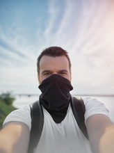 Selfie Of Man With Black Buff On Face As Mask. Tourist Travel With Face Protection.