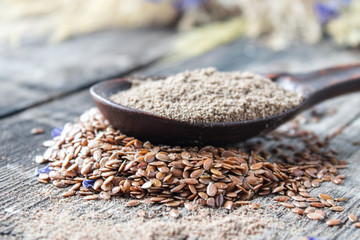 Wall Mural - Crushed flax seed in a wooden spoon on a pile of flaxseed.