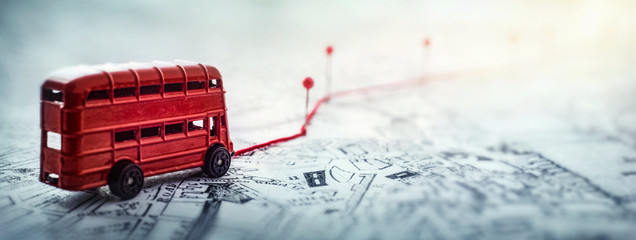 Red bus, pins and route laid on a map of the city. Concept on the  adventure, discovery, navigation, communication, logistics, geography, transport and travel topics.