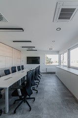 Interior of modern meeting room with office chairs and tv screen and wooden wall