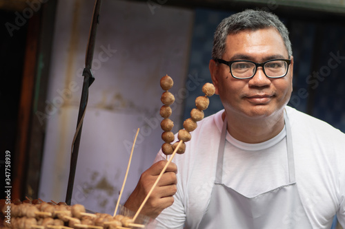 Cuadros en Lienzo street hawker man working with his delicious meatball skewer street food; concep