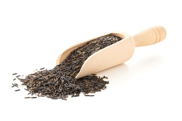 Wall Mural - Heap of uncooked, raw, black wild rice grains in wooden scoop over white