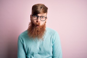 Sticker - Handsome Irish redhead man with beard wearing glasses over pink isolated background making fish face with lips, crazy and comical gesture. Funny expression.