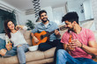 © Mediteraneo - Group of happy young friends having fun and drinking beer in home interior