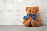 Fototapeta  - brown teddy bear with a blue bow sits on a white background