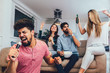 © Mediteraneo - Group of friends playing karaoke at home. Concept about friendship, home entertainment and people