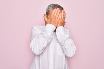 Sticker - Senior handsome grey-haired man wearing elegant shirt over isolated pink background with sad expression covering face with hands while crying. Depression concept.