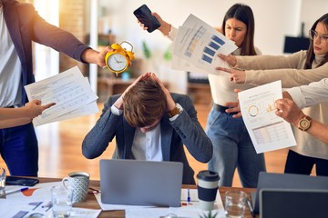 Canvas Print - Group of business workers working together. Partners stressing one of them at the office