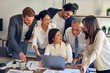 © Krakenimages.com - Group of business workers smiling happy and confident. One of them sitting and partners standing around. Working together with smile on face looking at the laptop at the office