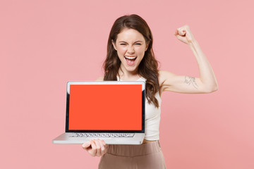 Wall Mural - Happy young brunette woman girl in light casual clothes isolated on pink background. People lifestyle concept. Mock up copy space. Hold laptop pc computer with blank empty screen doing winner gesture.