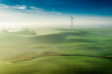 Wall Mural - Stunning foggy sunrise over green hills, view from above