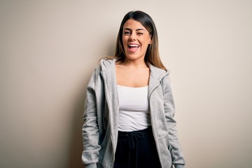 Poster - Young beautiful brunette sportswoman wearing sportswoman training over white background winking looking at the camera with sexy expression, cheerful and happy face.