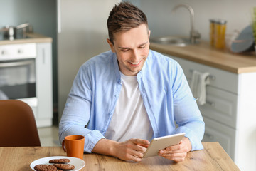 Sticker - Handsome man with tablet computer in kitchen at home