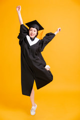 happy young woman in graduation gowns dancing for celebration