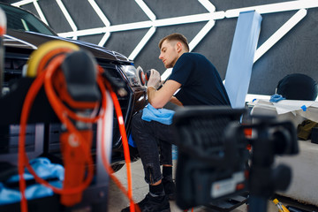 Wall Mural - Male worker polishes headlights, car detailing