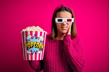 Wall Mural - Young beautiful girl watching movie using 3d glasses eating box with popcorns touching mouth with hand with painful expression because of toothache or dental illness on teeth. Dentist concept.