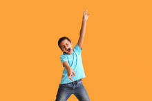 Little African-American Boy Dancing And Singing Against Color Background
