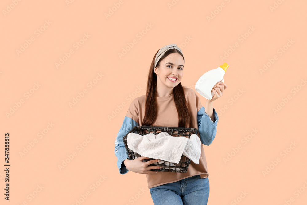 Beautiful young woman with laundry and detergent on color background