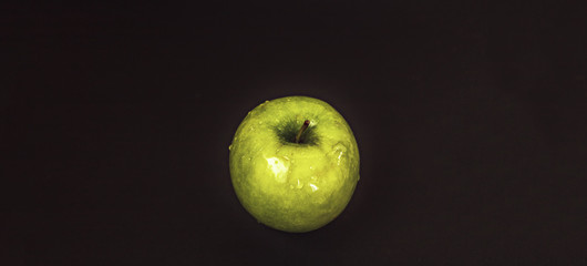 Juicy fresh green apple with water droplets on a black background with space for text. Banner