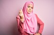 © Krakenimages.com - Young beautiful girl wearing muslim hijab standing over isolated pink background Doing Italian gesture with hand and fingers confident expression