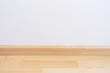 © Lifestyle Graphic - Wooden wall base skirting, finishing material with wood laminate floor and white mortar wall.