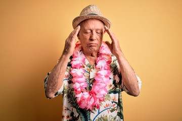 Poster - Grey haired senior man wearing summer hat and hawaiian lei over yellow background with hand on head for pain in head because stress. Suffering migraine.