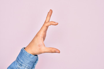 Hand of caucasian young man showing fingers over isolated pink background picking and taking invisible thing, holding object with fingers showing space