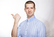 © Arsentyev Vladimir - portrait of a pretty successful man in a classic blue shirt; Shows his thumb to the side; look into the camera. Isolated