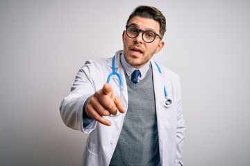 Wall Mural - Young doctor man with blue eyes wearing medical coat and stethoscope over isolated background pointing displeased and frustrated to the camera, angry and furious with you