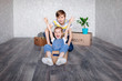 © marinatynik - Brother rides sister in a cardboard box. Children play with boxes at home in quarantine. A boy and a girl have moved into a new apartment and are happily playing without toys.