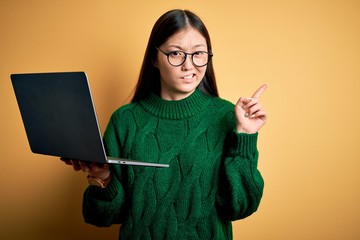 Sticker - Young asian business woman wearing glasses and working using computer laptop Pointing aside worried and nervous with forefinger, concerned and surprised expression