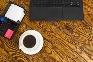 Poster - Laptop with cup of coffee on old brown wooden table. Top view to Notebook with cup of fresh coffee in home office in village.