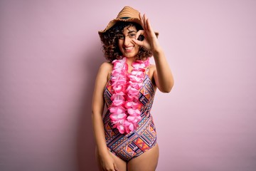 Poster - Young beautiful arab woman on vacation wearing swimsuit and hawaiian lei flowers smiling positive doing ok sign with hand and fingers. Successful expression.