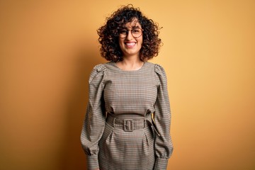 Sticker - Beautiful arab business woman wearing dress and glasses standing over yellow background with a happy and cool smile on face. Lucky person.