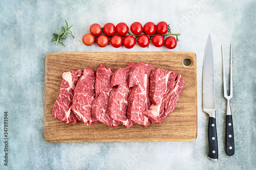 Photo Fresh raw beef steaks with pepper and tomatoes on wooden cutting board board
