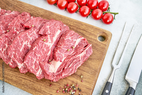 Fresh raw beef steaks with pepper and tomatoes on wooden cutting board Canvas Print