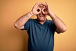 © Krakenimages.com - Middle age handsome hoary man wearing casual polo and glasses over yellow background doing ok gesture like binoculars sticking tongue out, eyes looking through fingers. Crazy expression.