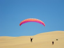 Man Paragliding In Desert Against Clear Blue Sky