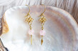 Tiny elegant female earrings with mineral stone beads on natural white shell background