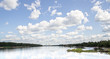River coastline with forest. Cirrus clouds in the blue sky