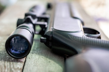 Sniper rifle lies on a wooden background. Optical sight close-up. The concept of hunting.