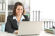 © PheelingsMedia - Happy executive lady working on laptop at office