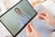 © Михаил Решетников - A woman is lying in bed with heat and is holding a thermometer. A friendly doctor talks to a sick patient by video link. Therapist on a laptop screen. Online medical consultation during the quarantine