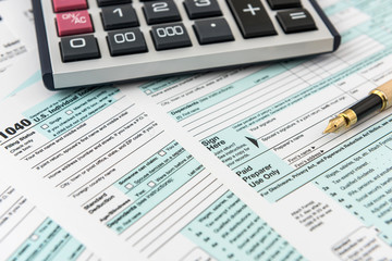 Tax form, pen and calculator at office desk